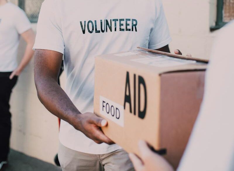Man in White Crew Neck T-shirt Holding Brown Box